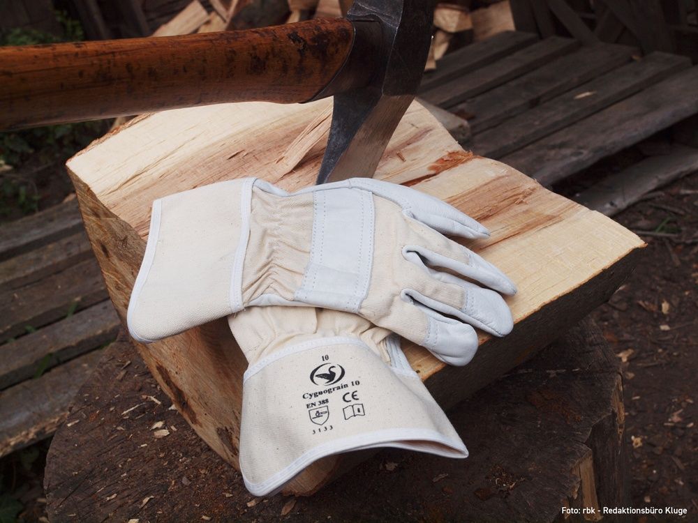 Schwan Lederhandschuhe auf einem Holzstück mit Axt